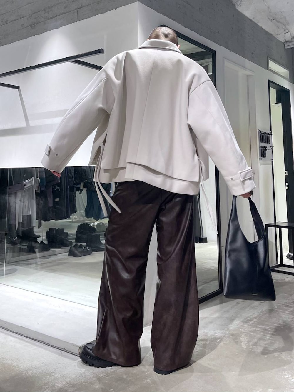 ブラック系のトートバッグ、ホワイト系のブルゾン、イエロー系のニット/セーターを着用したメンズの秋コーディネートの3枚目の写真