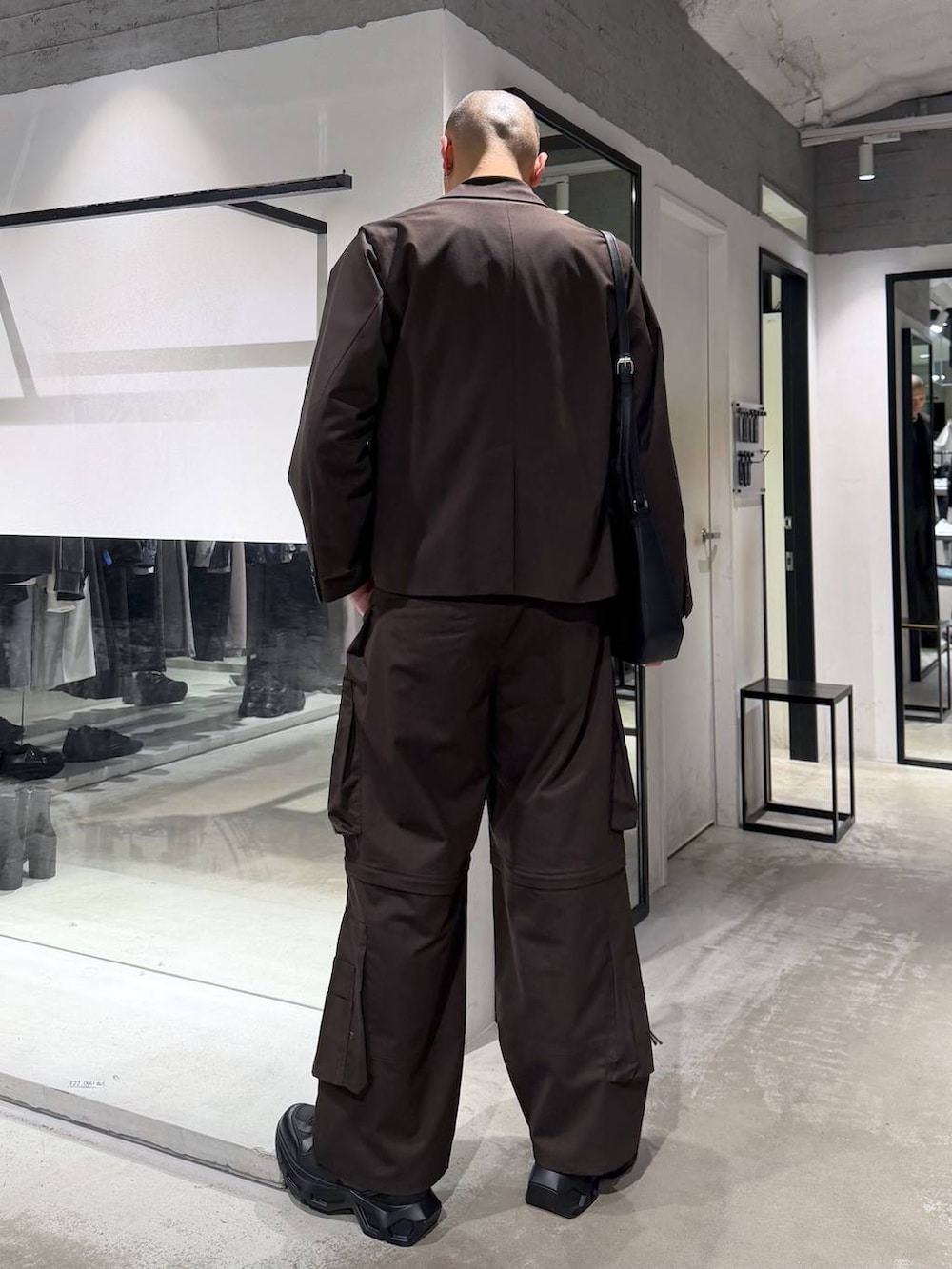 ブラック系のスニーカー、ブラウン系のテーラードジャケット、ブラウン系のカーゴパンツを着用したメンズの春コーディネートの3枚目の写真