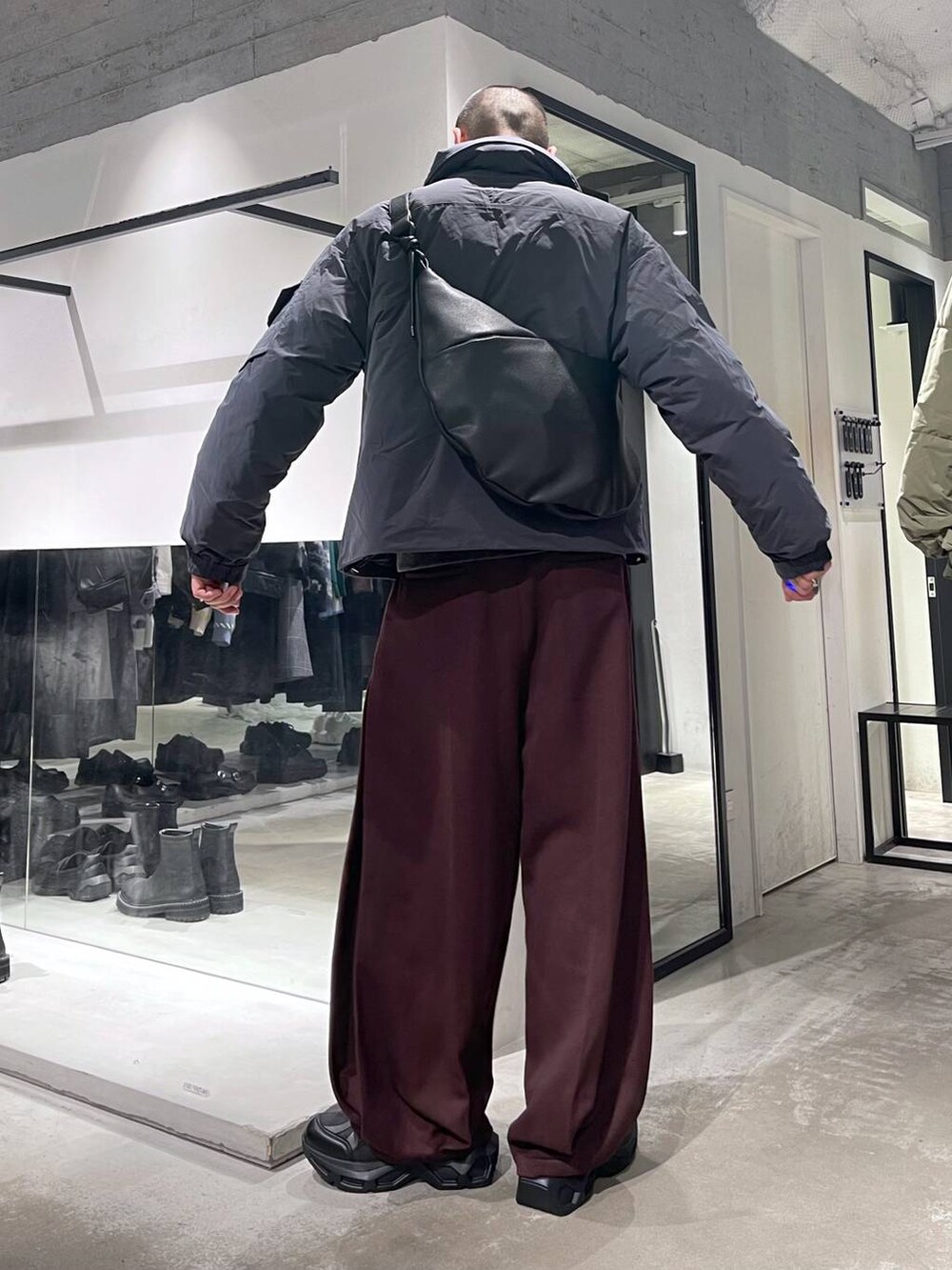 グレー系のダウンジャケット/コート、ブラック系のスニーカー、ブラック系のショルダーバッグを着用したメンズの秋コーディネートの3枚目の写真