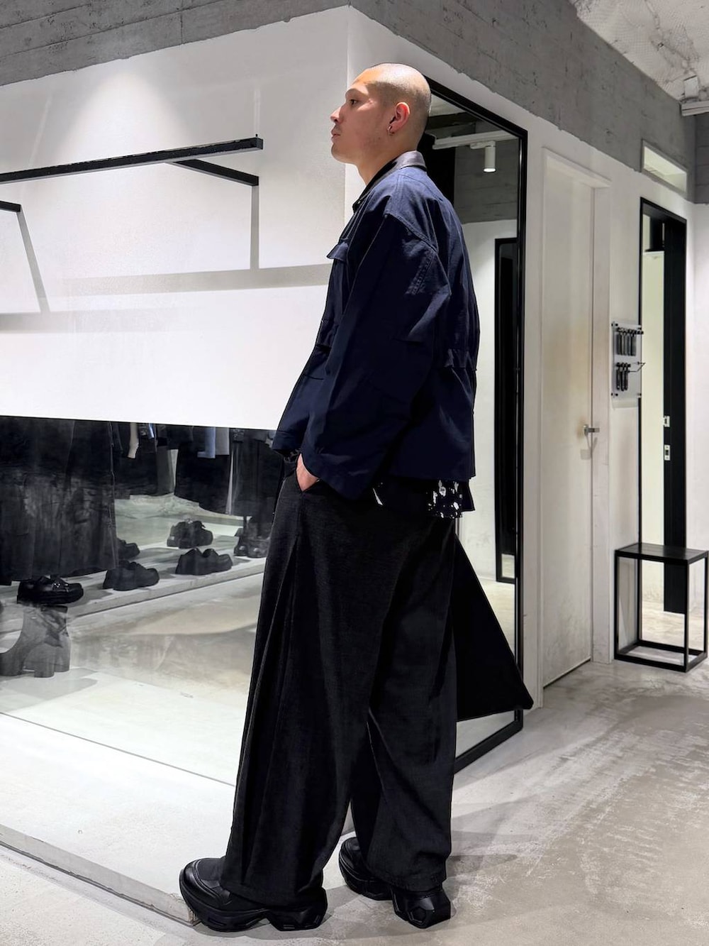 ブラック系のスニーカー、ブラック系のスラックス、ブラック系のトートバッグを着用したメンズの春コーディネートの2枚目の写真