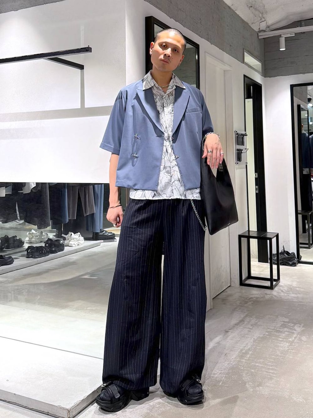 ブラック系のトートバッグ、ブラック系のサンダル、ブルー系のスラックスを着用したメンズの春コーディネートの2枚目の写真