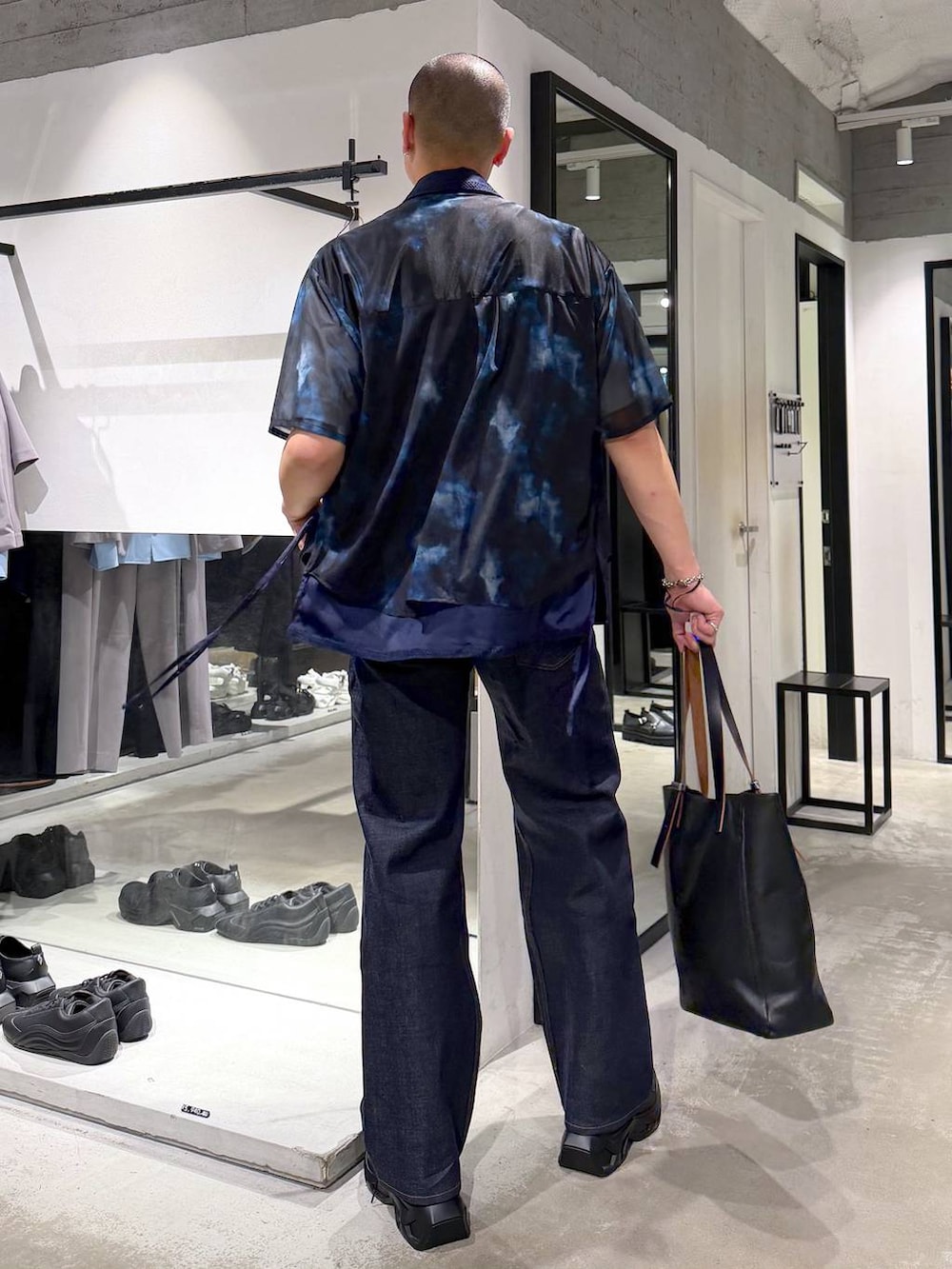 ブラック系のスニーカー、ホワイト系のTシャツ/カットソー、ブラック系のトートバッグを着用したメンズの夏コーディネートの3枚目の写真