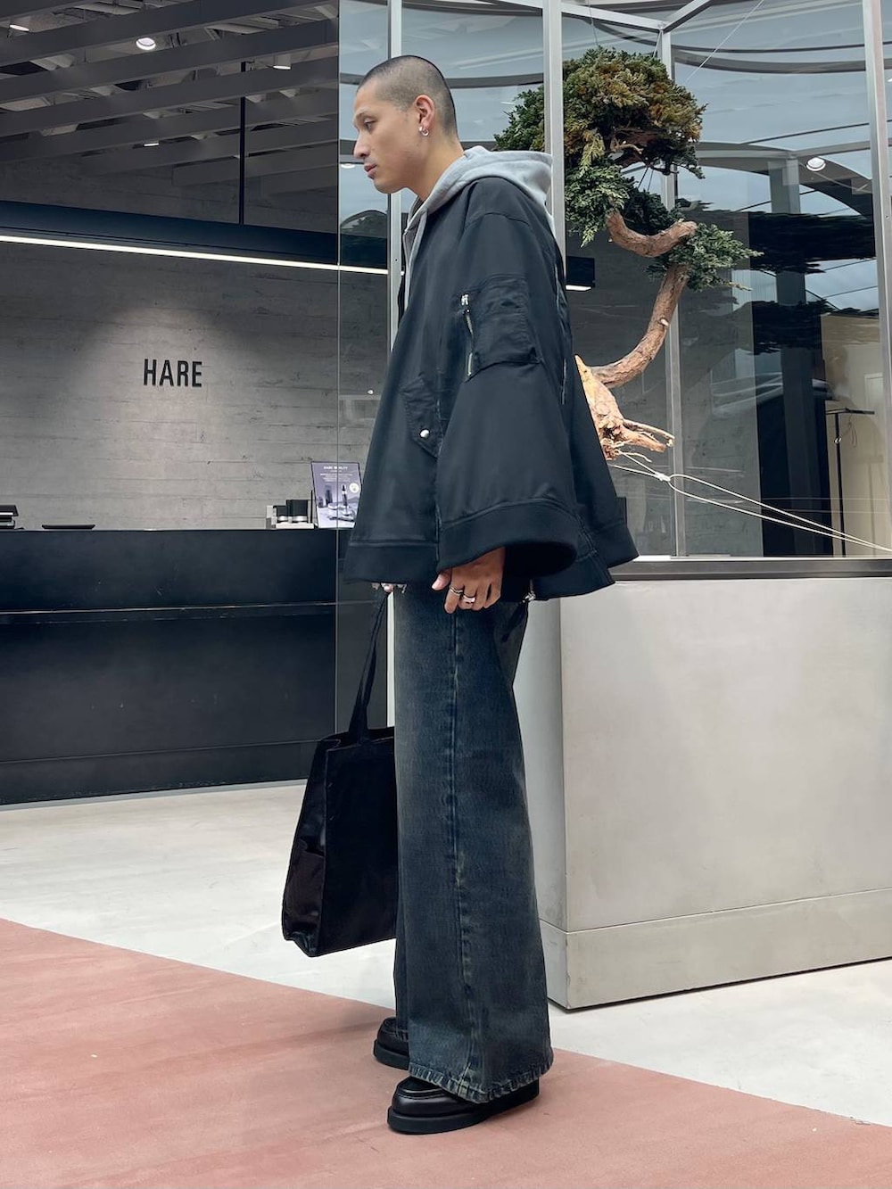 グレー系のパーカー、ブラック系のトートバッグ、ブラック系のローファーを着用したメンズの秋コーディネートの3枚目の写真