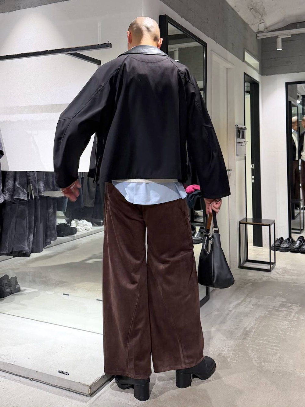 ブラック系のブルゾン、ブラウン系のスラックス、ホワイト系のニット/セーターを着用したメンズの秋コーディネートの3枚目の写真