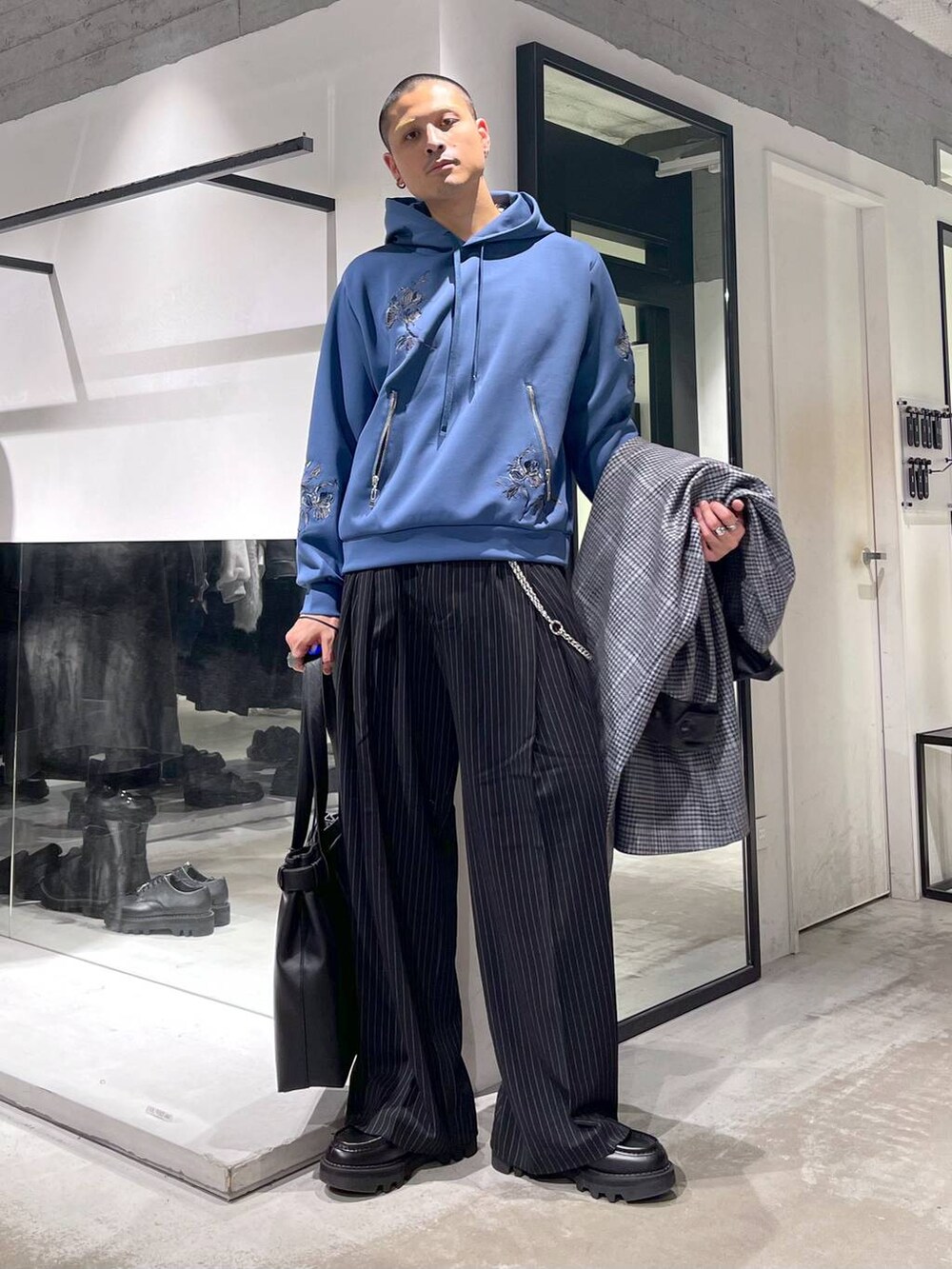 ベージュ系のステンカラーコート、ブラック系のトートバッグ、ブラック系のドレスシューズを着用したメンズの秋コーディネートの5枚目の写真