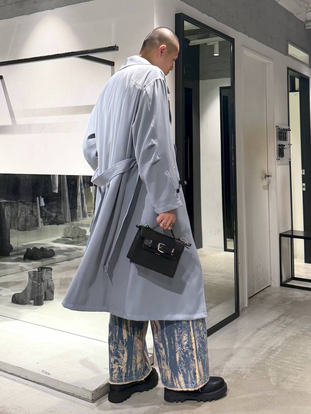 ブラック系のドレスシューズ、ブラック系のハンドバッグ、グリーン系のトレンチコートを着用したメンズの冬コーディネートの4枚目の写真