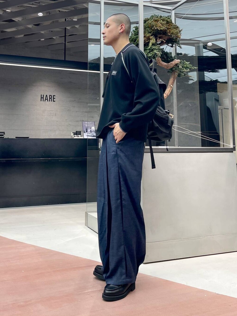 ブルー系のスラックス、ブラック系のローファー、ブラック系のバックパック/リュックを着用したメンズの秋コーディネートの2枚目の写真