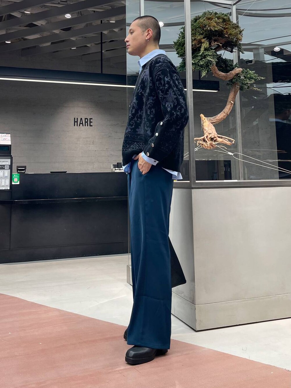 ブルー系のスラックス、ブラック系のカーディガン/ボレロ、ブラック系のトートバッグを着用したメンズの秋コーディネートの2枚目の写真