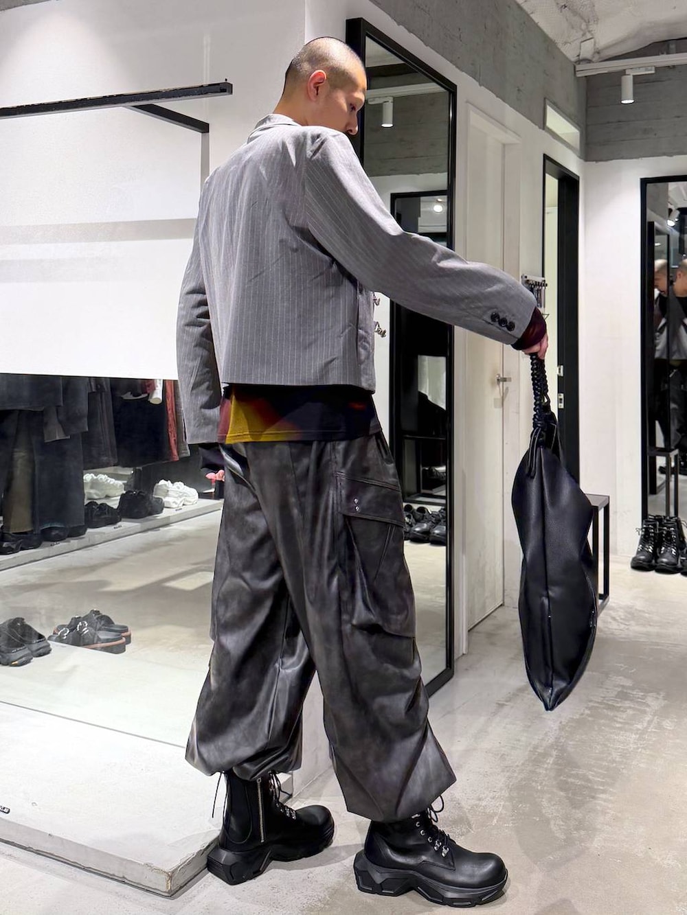ブラック系のトートバッグ、ブラック系のブーツ、オレンジ系のTシャツ/カットソーを着用したメンズの秋コーディネートの4枚目の写真