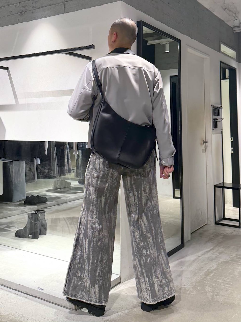 ブラック系のドレスシューズ、ブラック系のショルダーバッグ、グレー系のデニムパンツを着用したメンズの春コーディネートの3枚目の写真