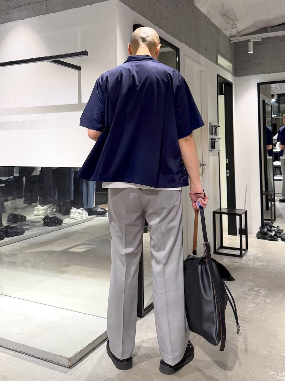 グレー系のスラックス、ブラック系のサンダル、ブラック系のトートバッグを着用したメンズの春コーディネートの3枚目の写真