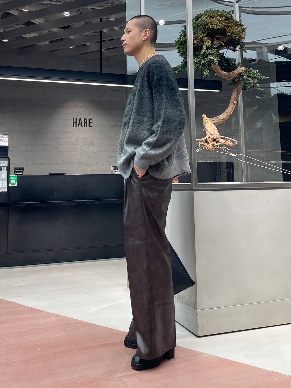 ブラック系のカーディガン/ボレロ、ブラウン系のスラックス、ブラック系のトートバッグを着用したメンズの秋コーディネートの2枚目の写真