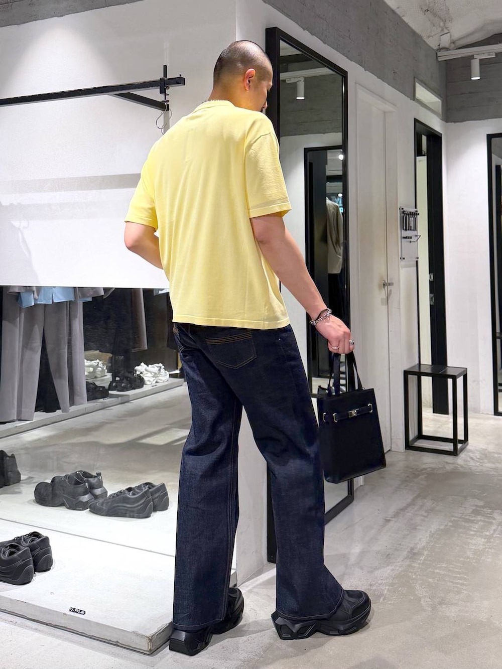 ブラック系のスニーカー、ホワイト系のTシャツ/カットソー、ブラック系のデニムパンツを着用したメンズの夏コーディネートの4枚目の写真