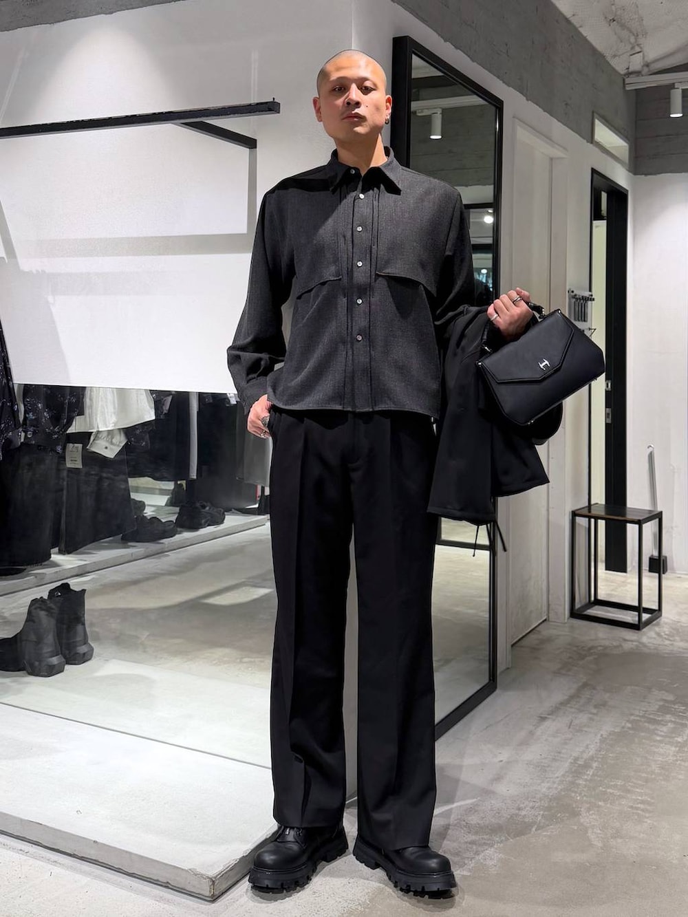 ブラック系のスラックス、ブラック系のハンドバッグ、ブラック系のドレスシューズを着用したメンズの春コーディネートの5枚目の写真