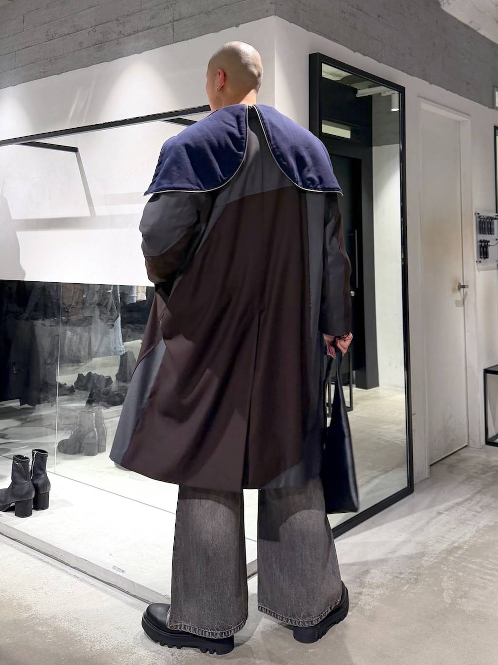 ブラック系のトートバッグ、ブラウン系のデニムパンツ、ブラック系のドレスシューズを着用したメンズの冬コーディネートの2枚目の写真