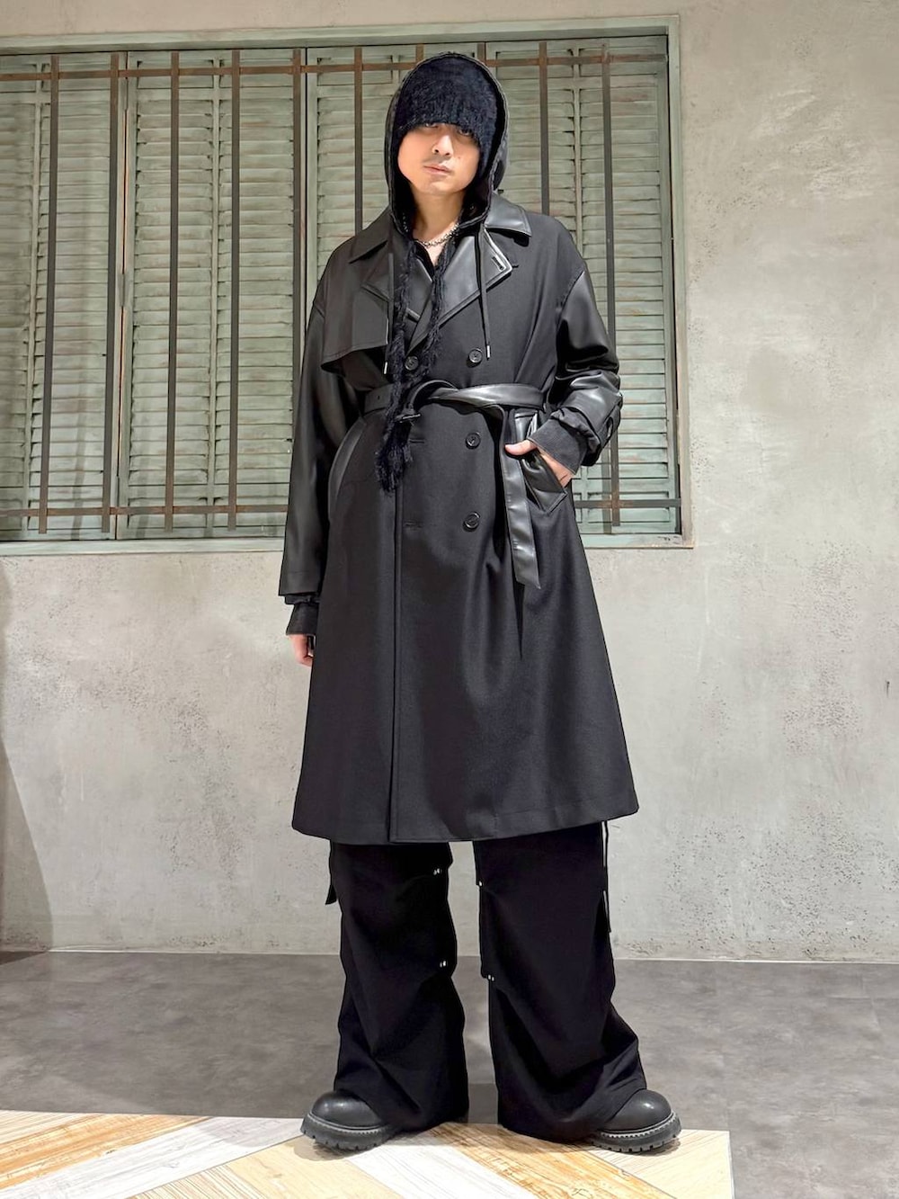 ブラック系のパーカー、ブラック系のブーツ、ブラック系のトレンチコートを着用したメンズの秋コーディネートの2枚目の写真