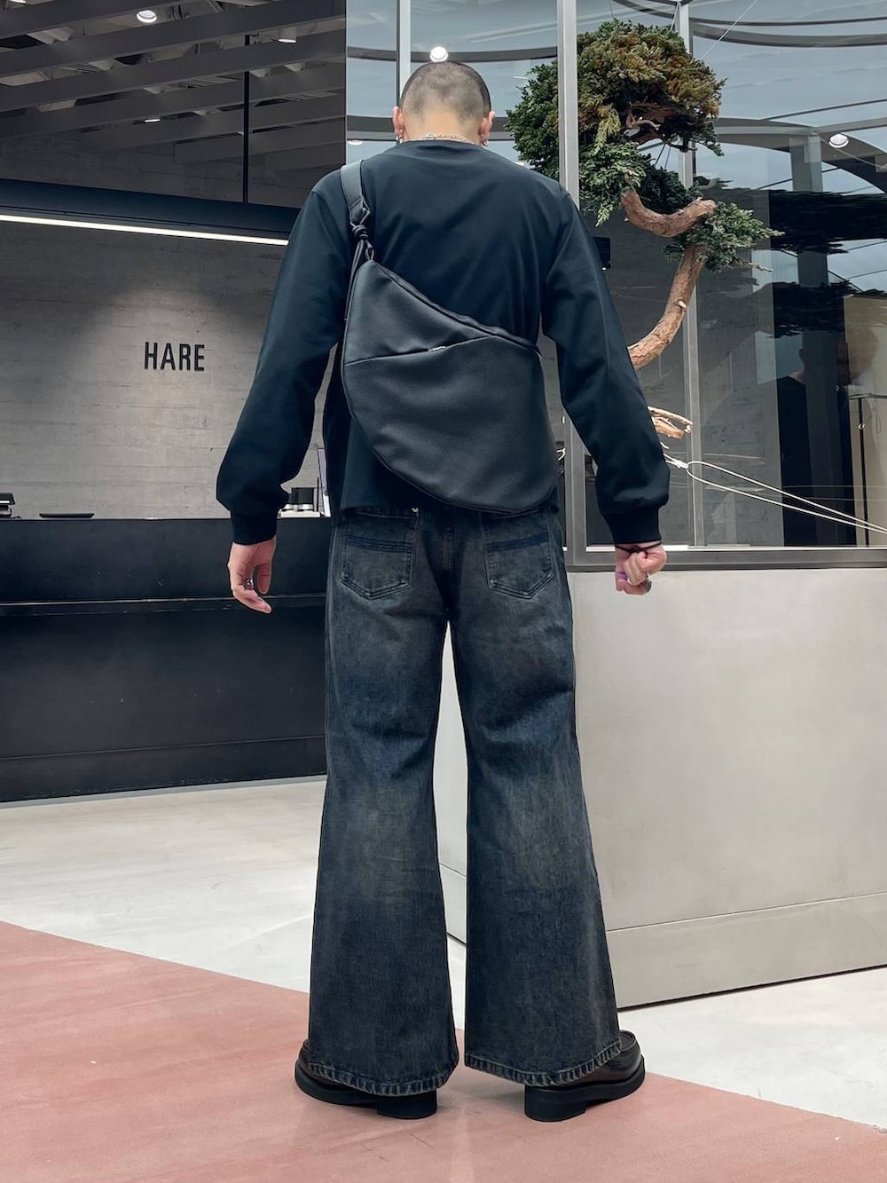 ブラック系のローファー、ブルー系のデニムパンツ、ブラック系のショルダーバッグを着用したメンズの秋コーディネートの3枚目の写真