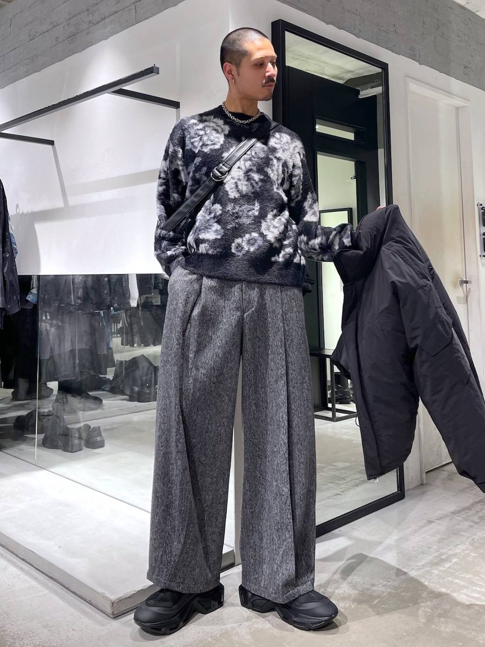 ブラック系のニット/セーター、ブラック系のダウンジャケット/コート、ブラック系のスラックスを着用したメンズの冬コーディネートの5枚目の写真