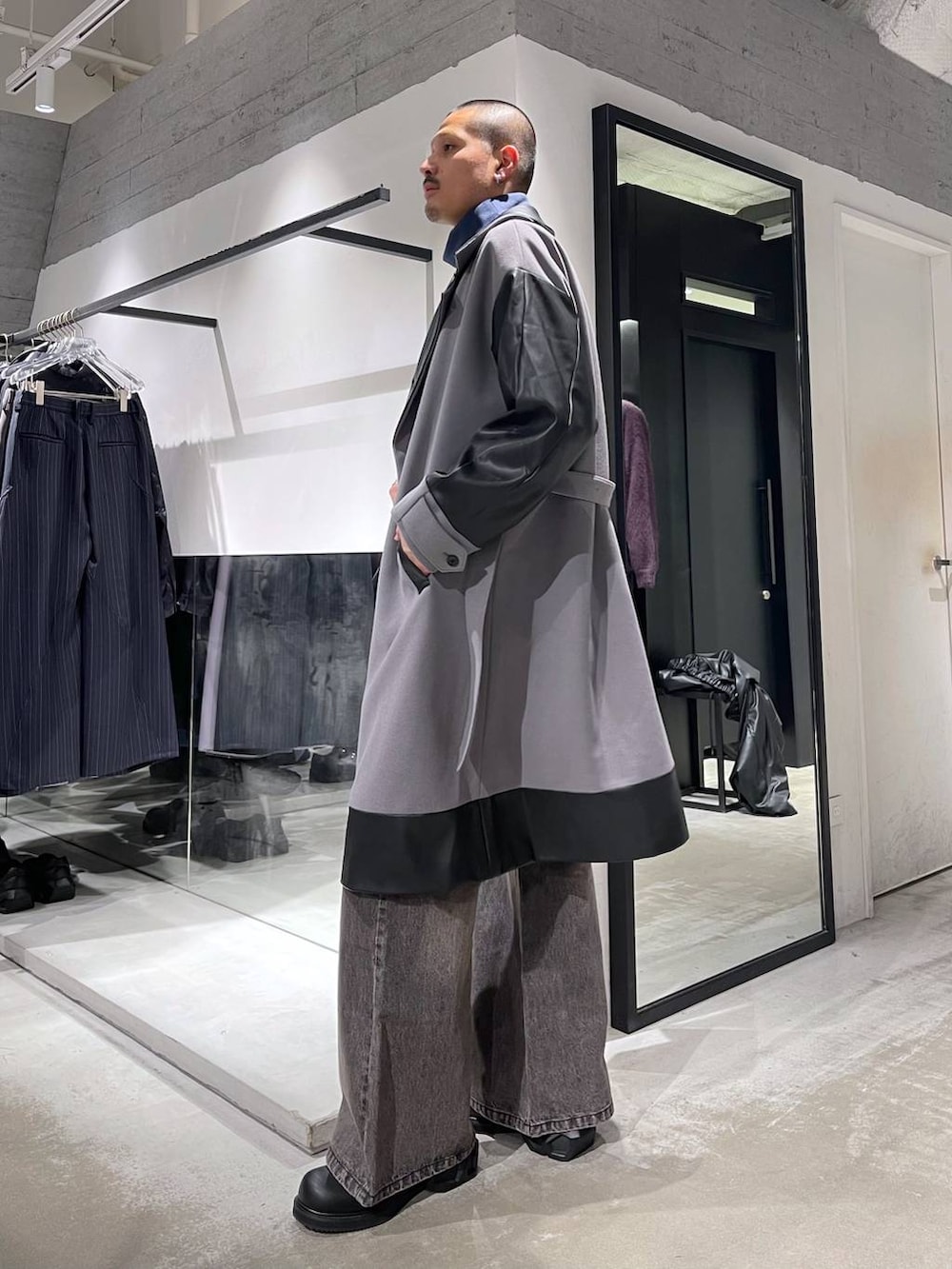 グレー系のトレンチコート、ブラウン系のデニムパンツ、ブラック系のドレスシューズを着用したメンズの冬コーディネートの2枚目の写真