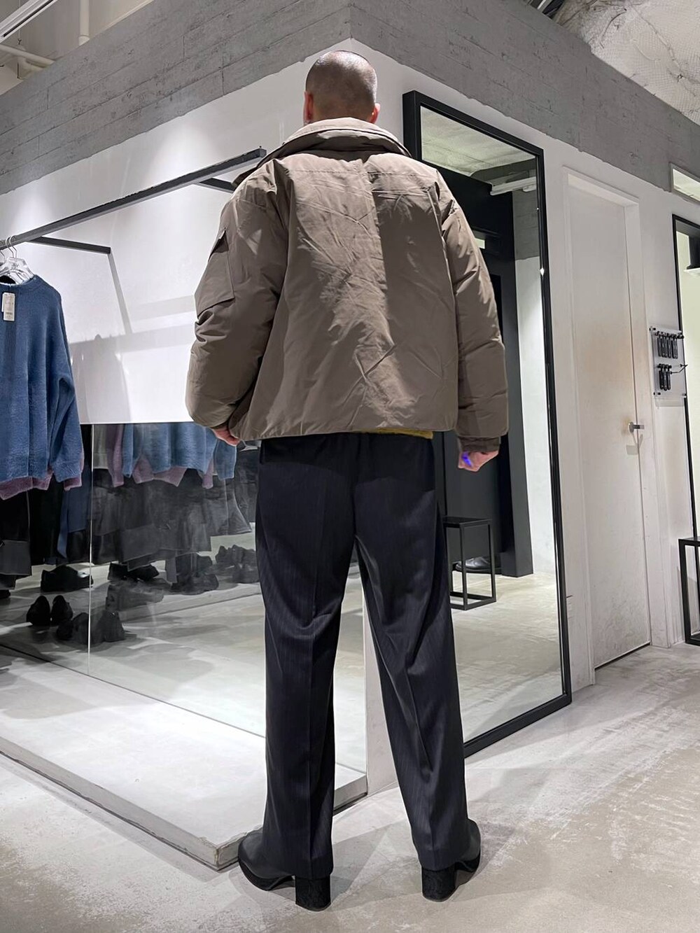 イエロー系のニット/セーター、ブラック系のトートバッグ、ブラウン系のダウンジャケット/コートを着用したメンズの冬コーディネートの3枚目の写真