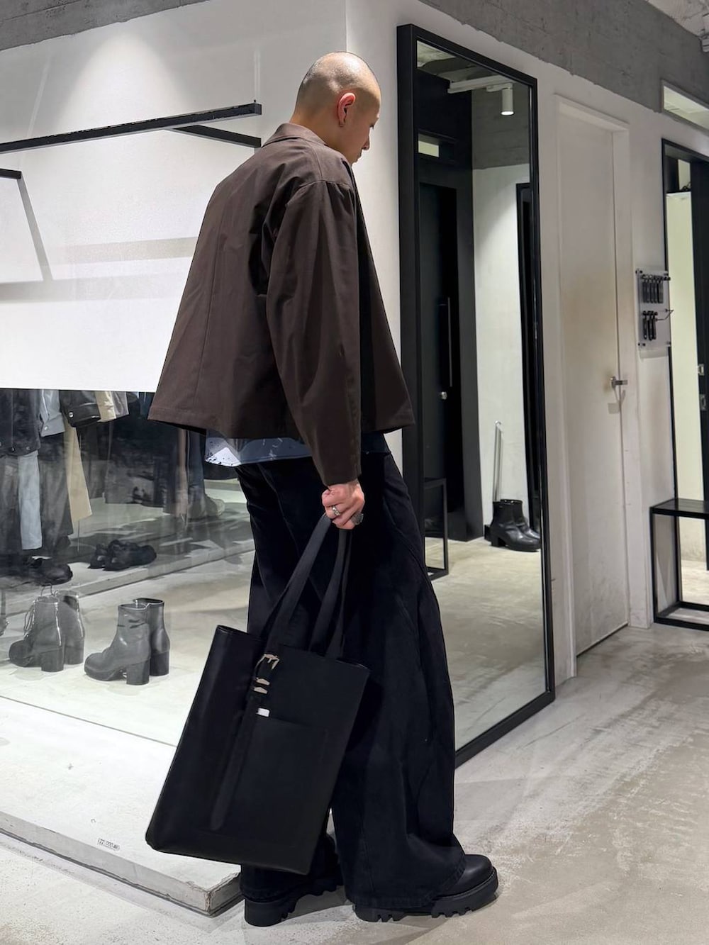 ブラック系のデニムパンツ、ブラック系のドレスシューズ、ブラック系のトートバッグを着用したメンズの冬コーディネートの4枚目の写真