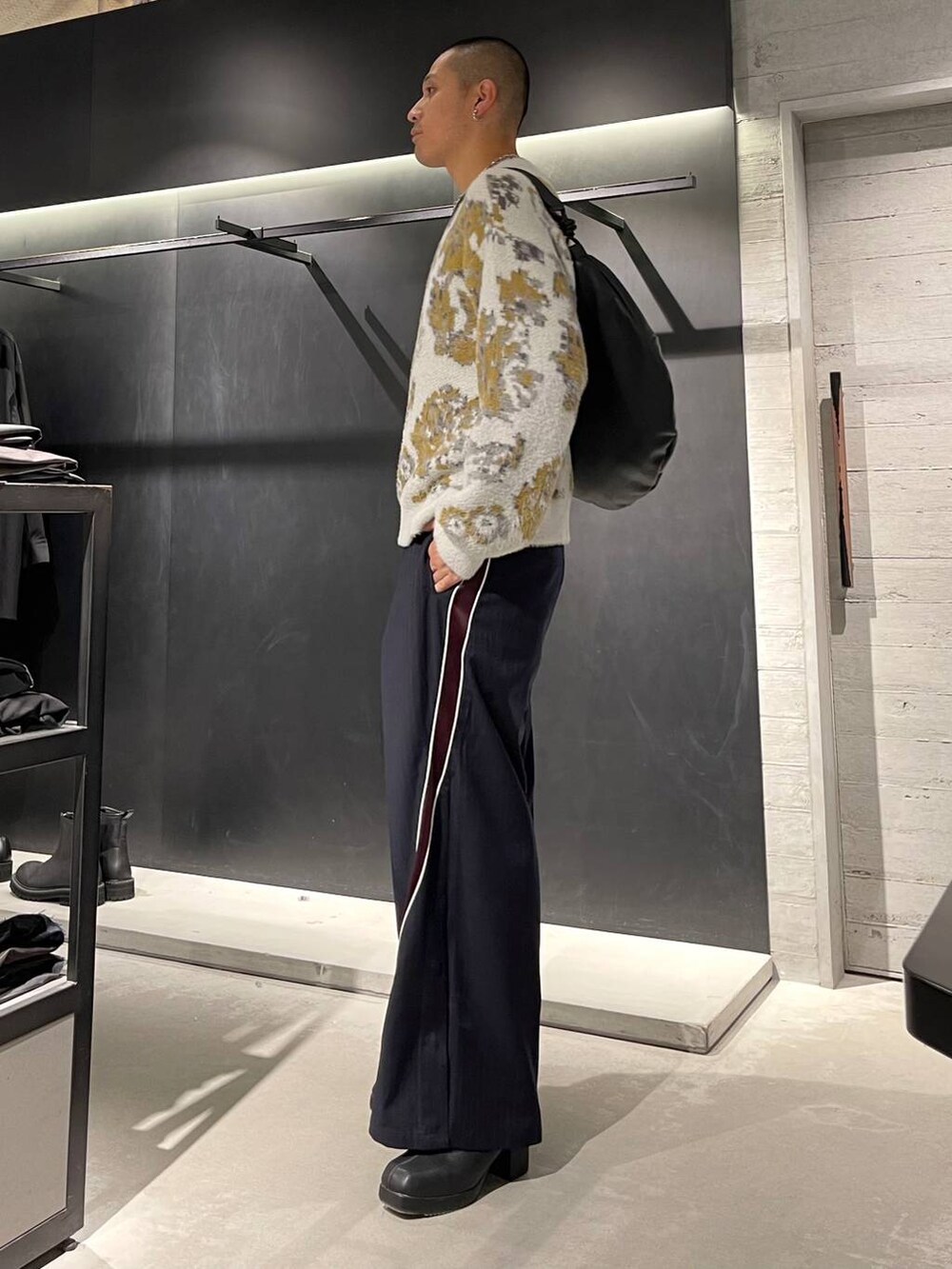 ホワイト系のニット/セーター、ブラック系のブーツ、ブラック系のショルダーバッグを着用したメンズの秋コーディネートの2枚目の写真