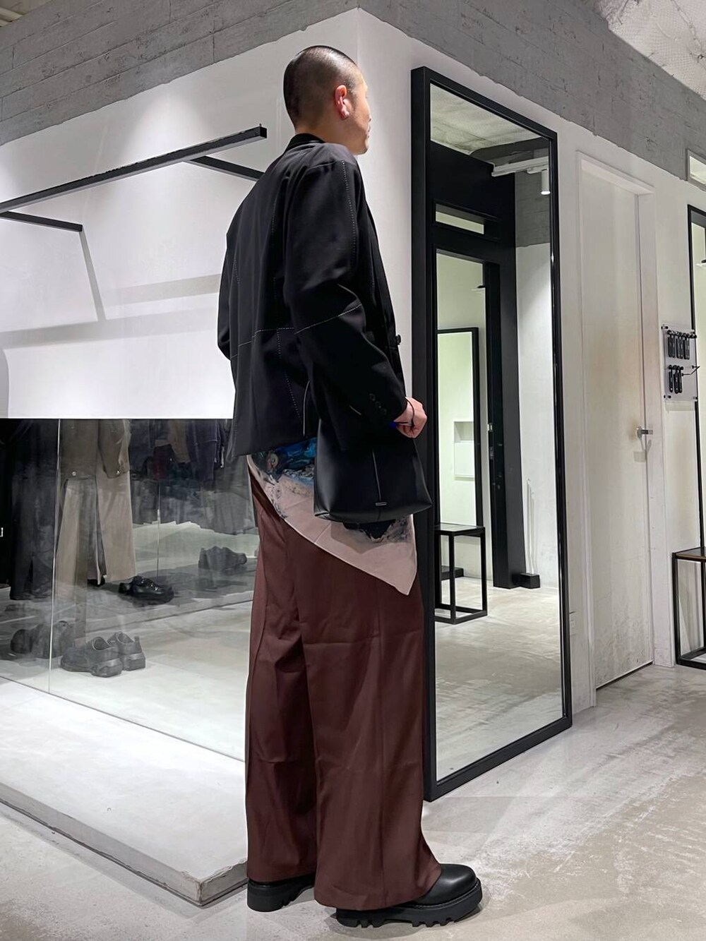 レッド系のスラックス、ブラック系のショルダーバッグ、ブラック系のドレスシューズを着用したメンズの冬コーディネートの4枚目の写真