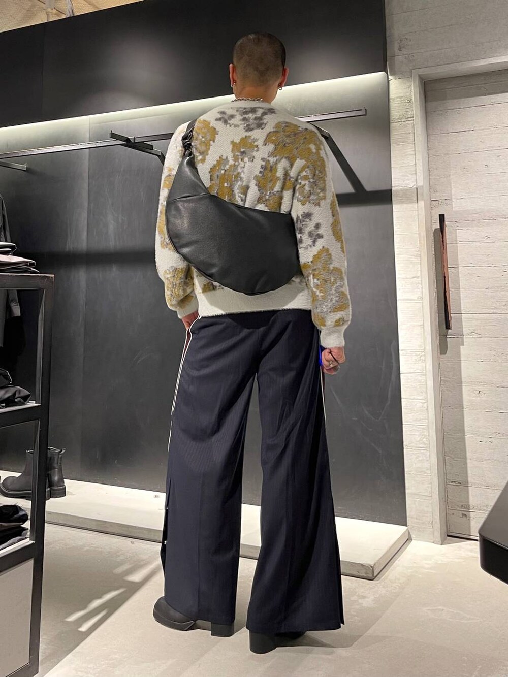 ホワイト系のニット/セーター、ブラック系のブーツ、ブラック系のショルダーバッグを着用したメンズの秋コーディネートの3枚目の写真