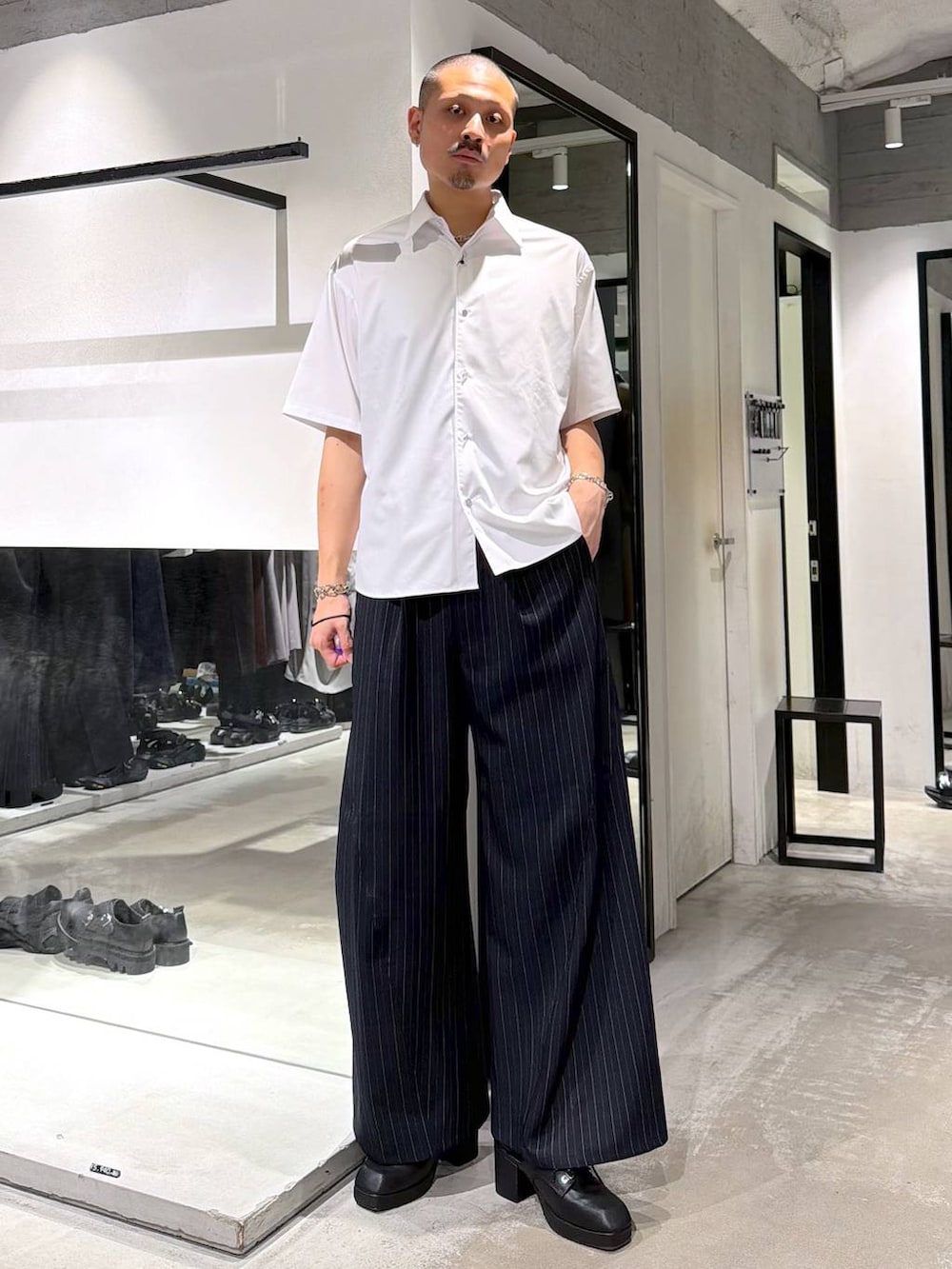 ブラック系のサンダル、ブルー系のスラックス、シルバー系のニット/セーターを着用したメンズの夏コーディネートの5枚目の写真