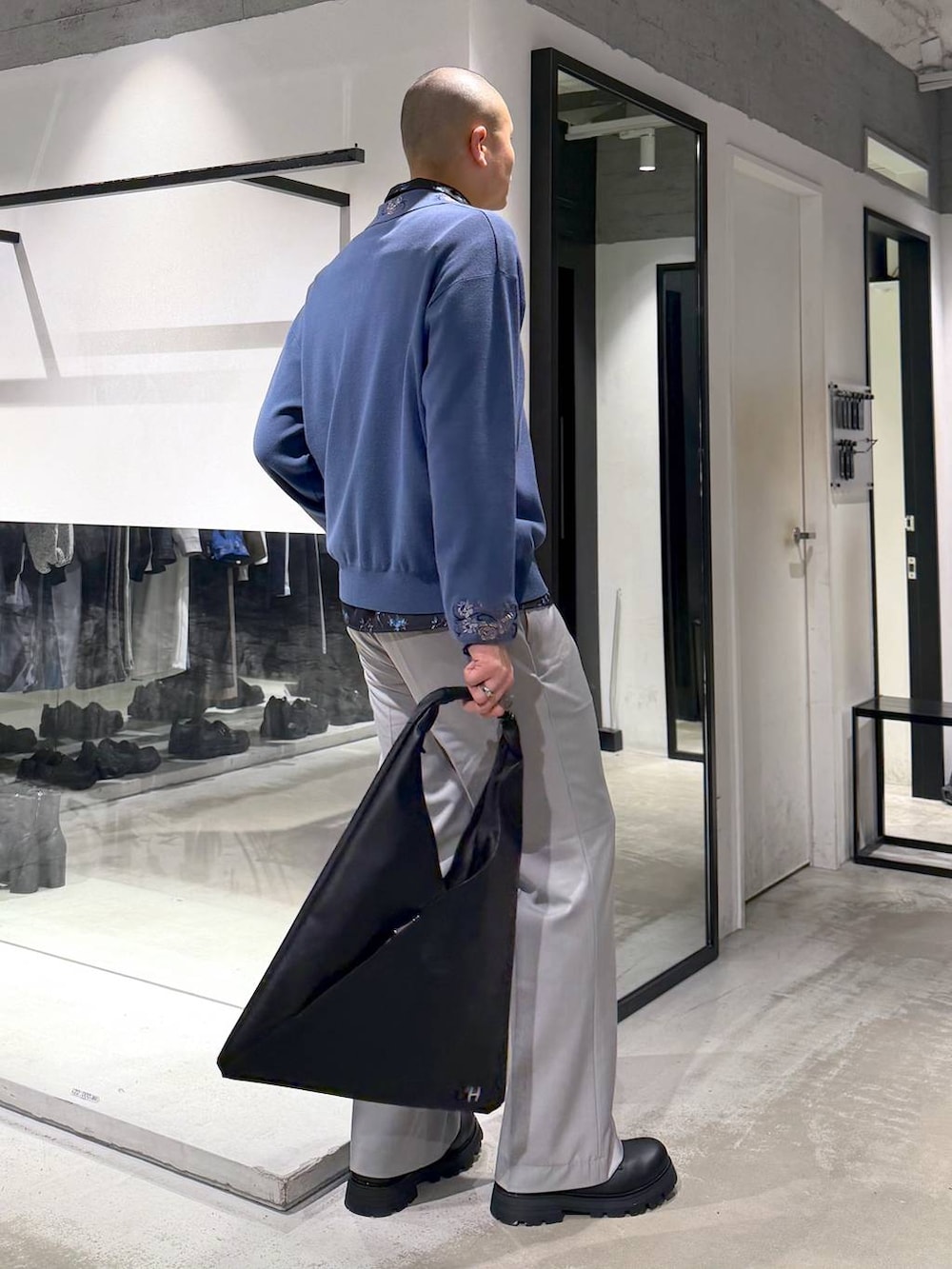 グレー系のスラックス、ブルー系のポロシャツ、ブラック系のドレスシューズを着用したメンズの春コーディネートの4枚目の写真