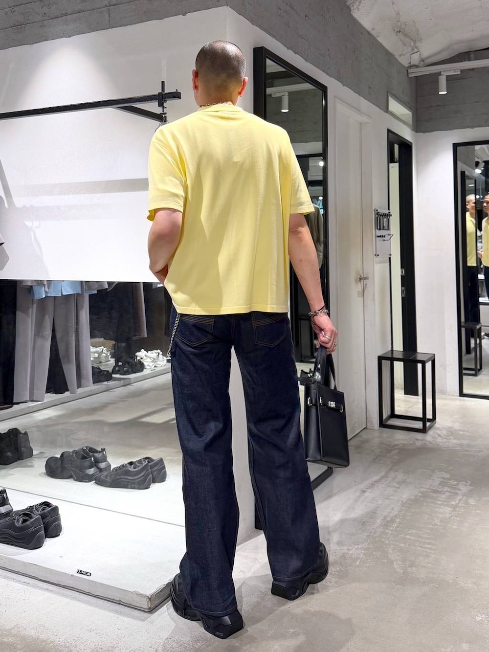ブラック系のスニーカー、ホワイト系のTシャツ/カットソー、ブラック系のデニムパンツを着用したメンズの夏コーディネートの3枚目の写真