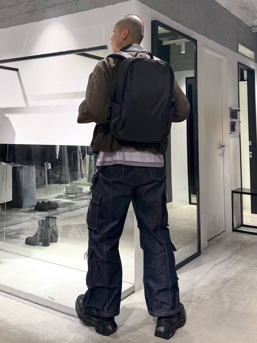 ブラック系のスニーカー、ブラウン系のブルゾン、ブラック系のバックパック/リュックを着用したメンズの春コーディネートの2枚目の写真