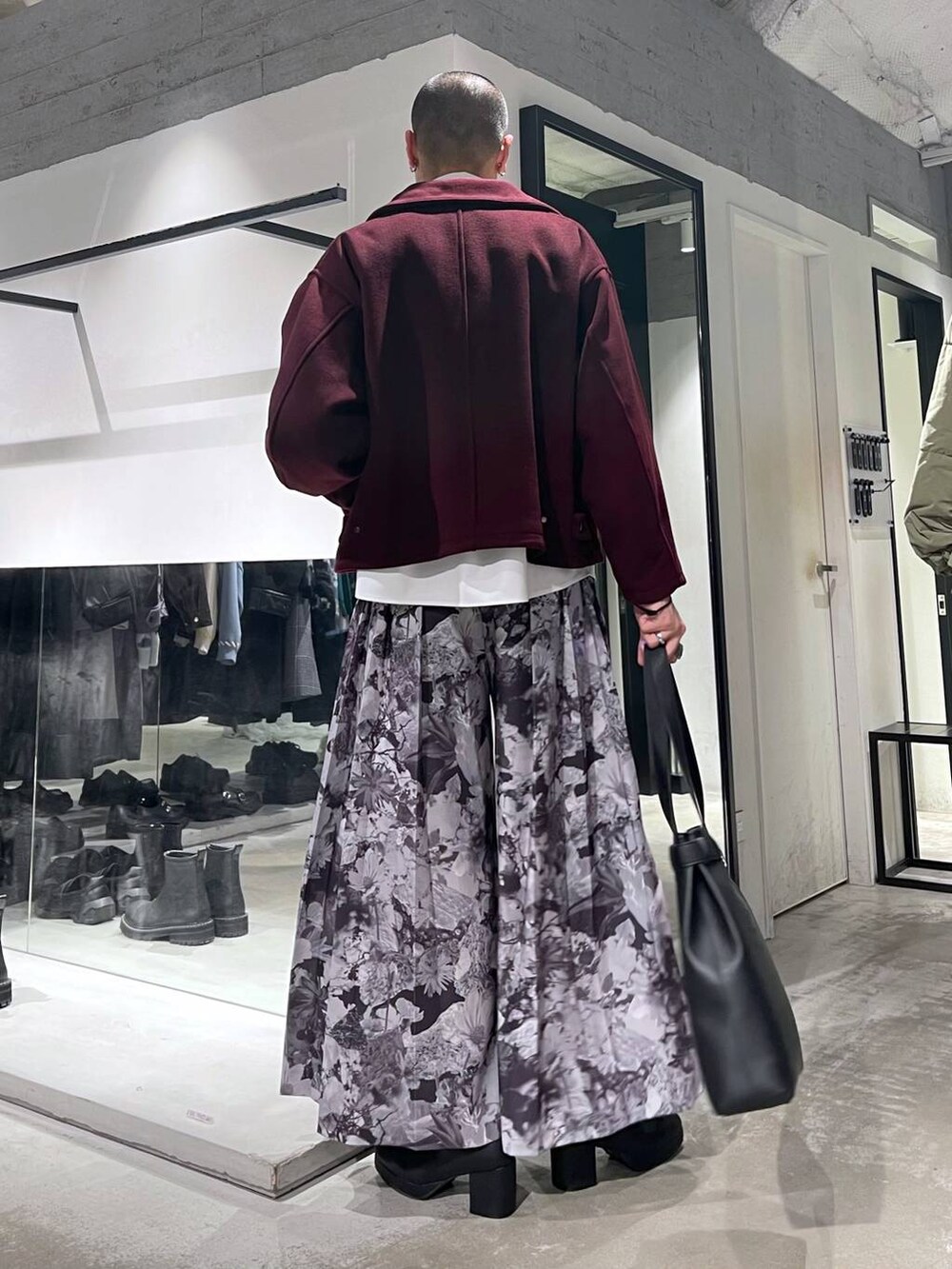 レッド系のブルゾン、ブラック系のトートバッグ、ブラック系のブーツを着用したメンズの秋コーディネートの3枚目の写真