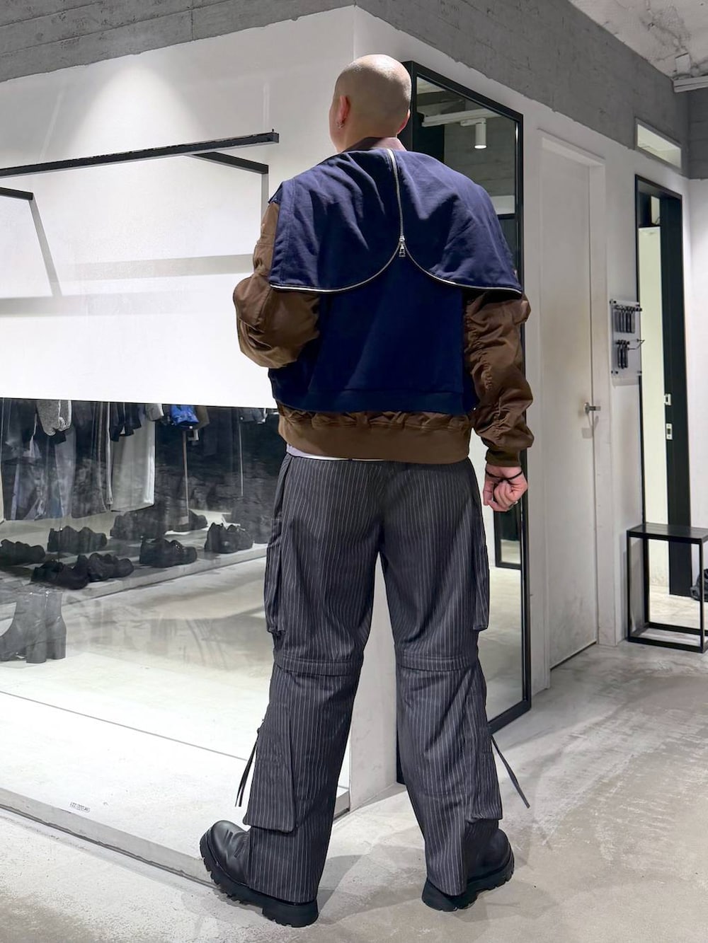 ブラック系のドレスシューズ、グレー系のカーゴパンツ、ブルー系のパーカーを着用したメンズの春コーディネートの3枚目の写真