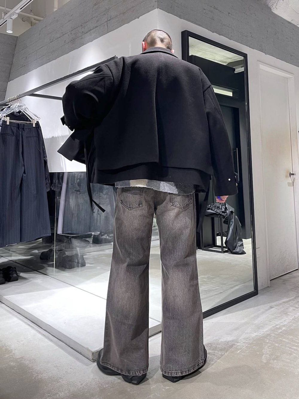 ブラック系のブルゾン、ブラック系のトートバッグ、ブラウン系のデニムパンツを着用したメンズの冬コーディネートの3枚目の写真