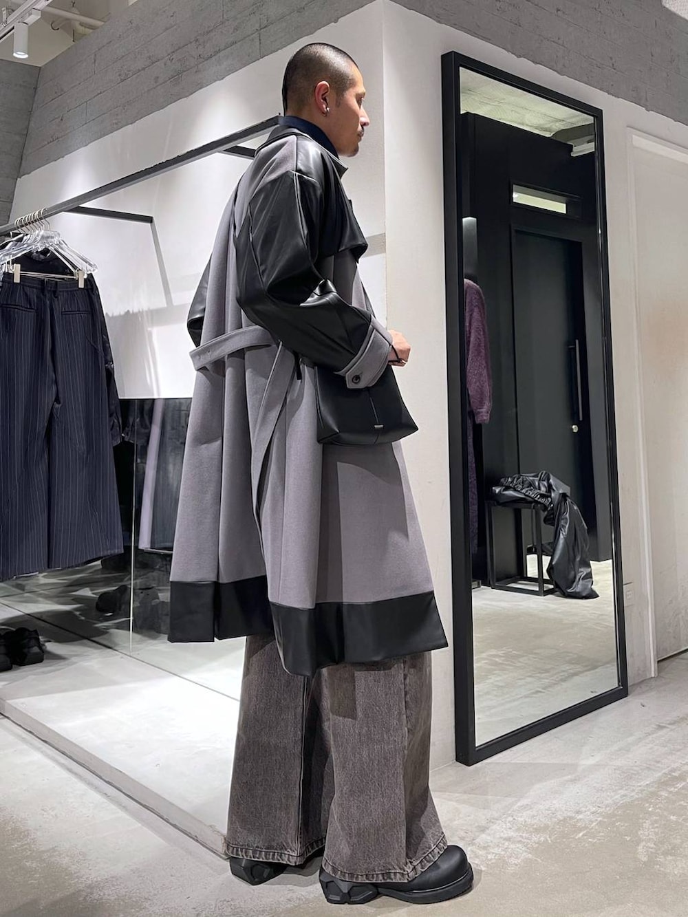 グレー系のトレンチコート、ブラウン系のデニムパンツ、ブラック系のドレスシューズを着用したメンズの冬コーディネートの4枚目の写真