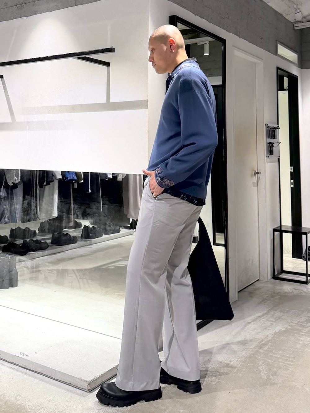 グレー系のスラックス、ブルー系のポロシャツ、ブラック系のドレスシューズを着用したメンズの春コーディネートの2枚目の写真