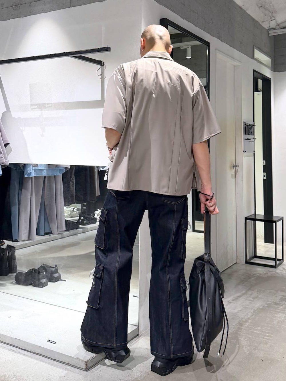 ブラック系のスニーカー、ブルー系のデニムパンツ、ブラック系のトートバッグを着用したメンズの夏コーディネートの3枚目の写真