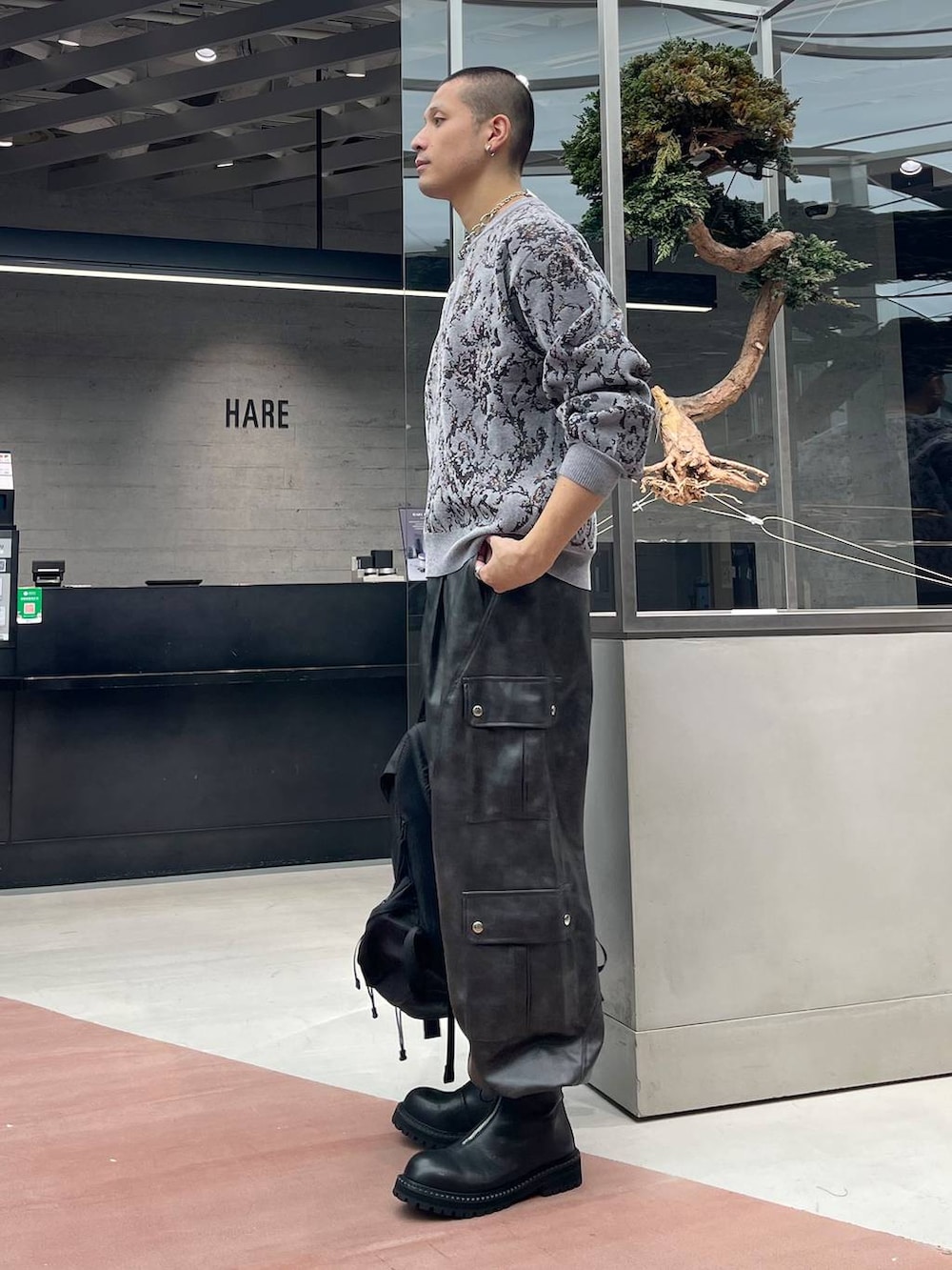 グレー系のニット/セーター、グレー系のカーゴパンツ、ブラック系のバックパック/リュックを着用したメンズの秋コーディネートの2枚目の写真