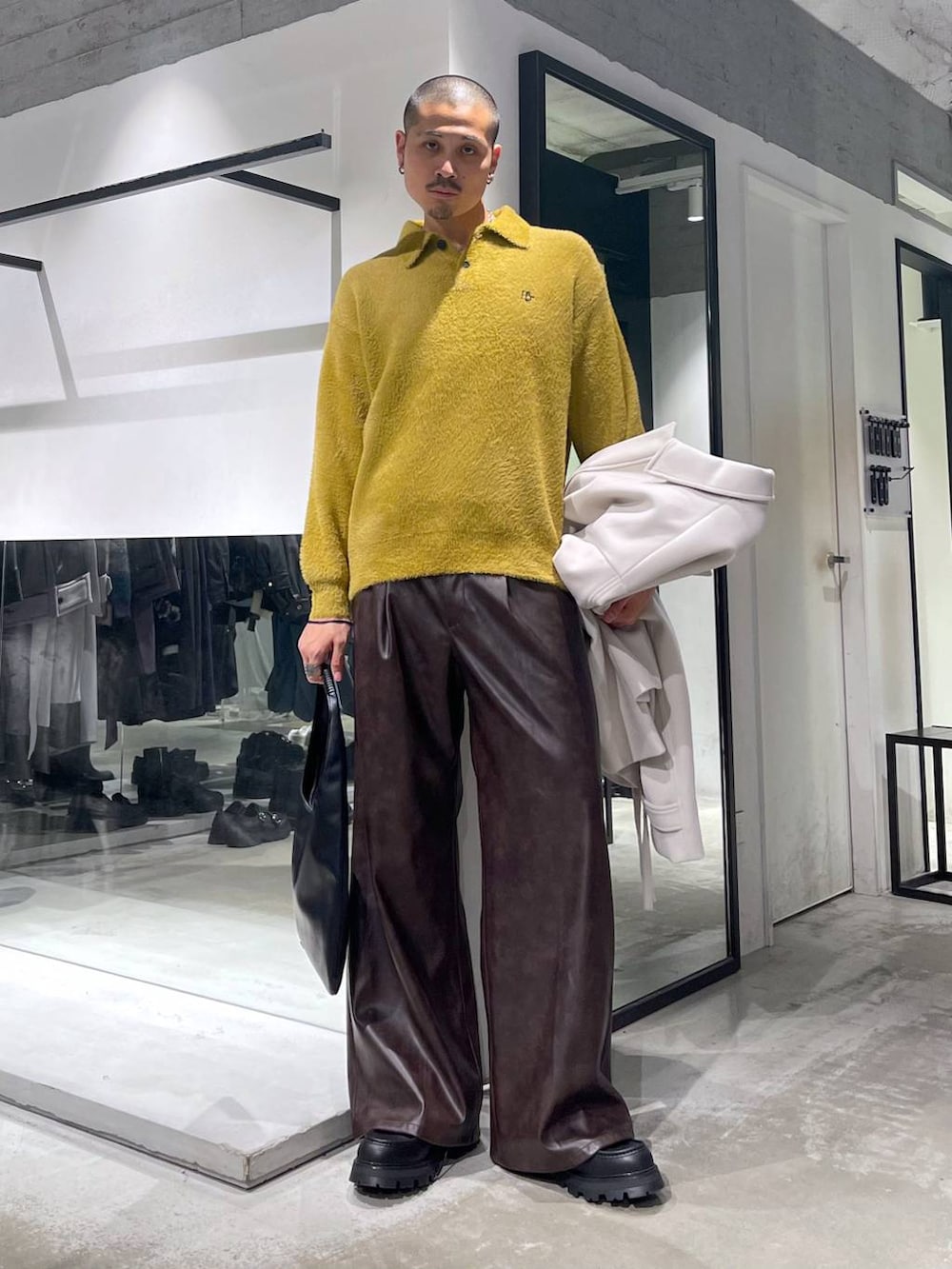 ブラック系のトートバッグ、ホワイト系のブルゾン、イエロー系のニット/セーターを着用したメンズの秋コーディネートの7枚目の写真