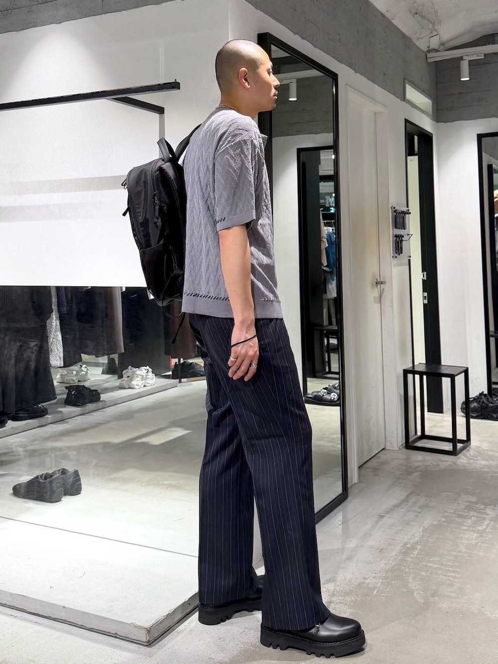 ブルー系のスラックス、ブラック系のドレスシューズ、ブラック系のバックパック/リュックを着用したメンズの夏コーディネートの4枚目の写真
