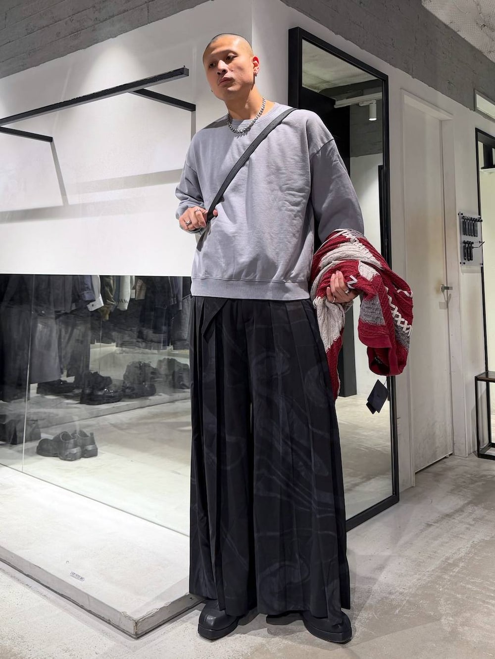 ブラック系のブルゾン、グレー系のその他パンツ、レッド系のカーディガン/ボレロを着用したメンズの冬コーディネートの6枚目の写真