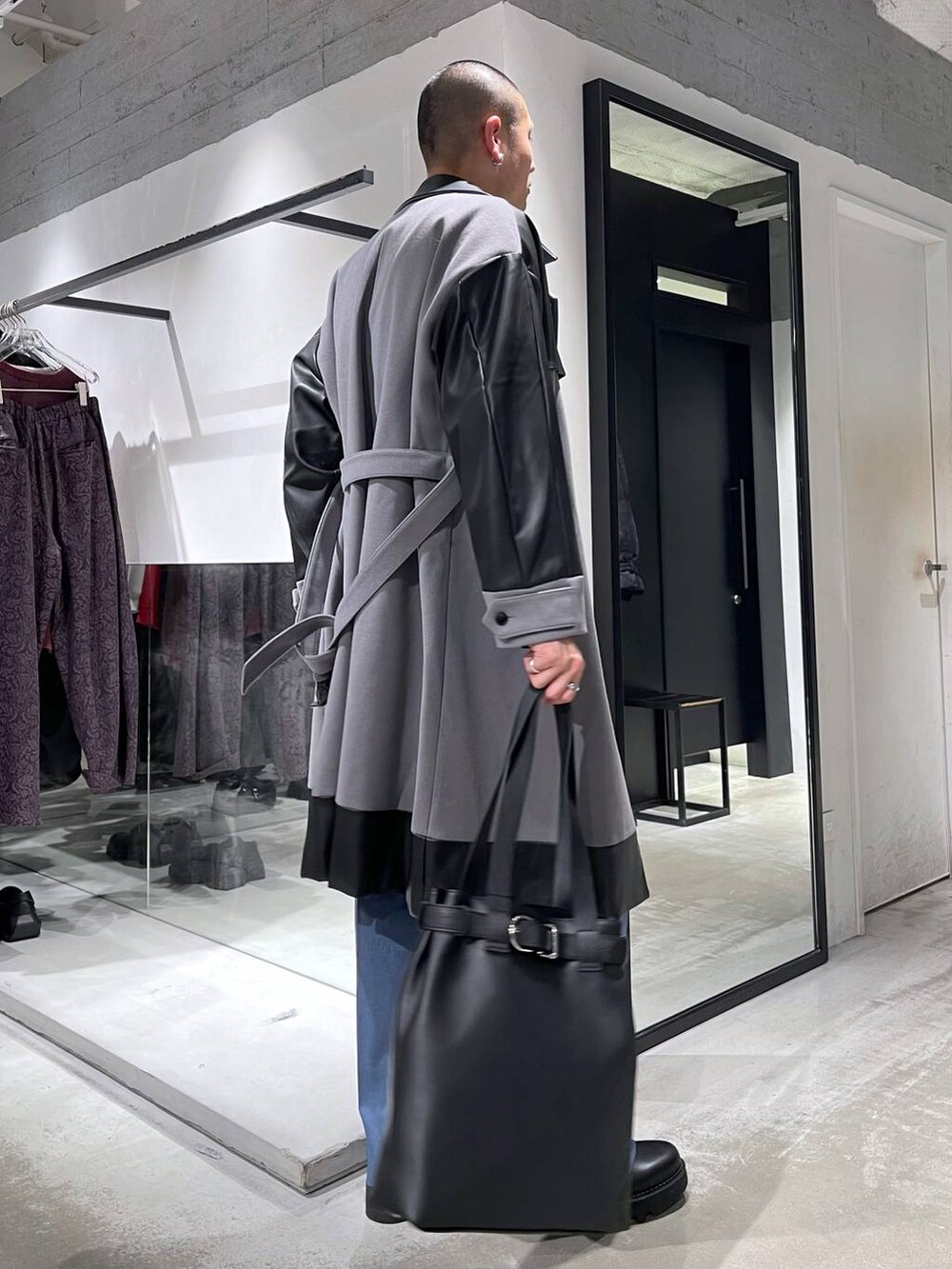 グレー系のトレンチコート、ブラック系のトートバッグ、ブラック系のニット/セーターを着用したメンズの冬コーディネートの4枚目の写真