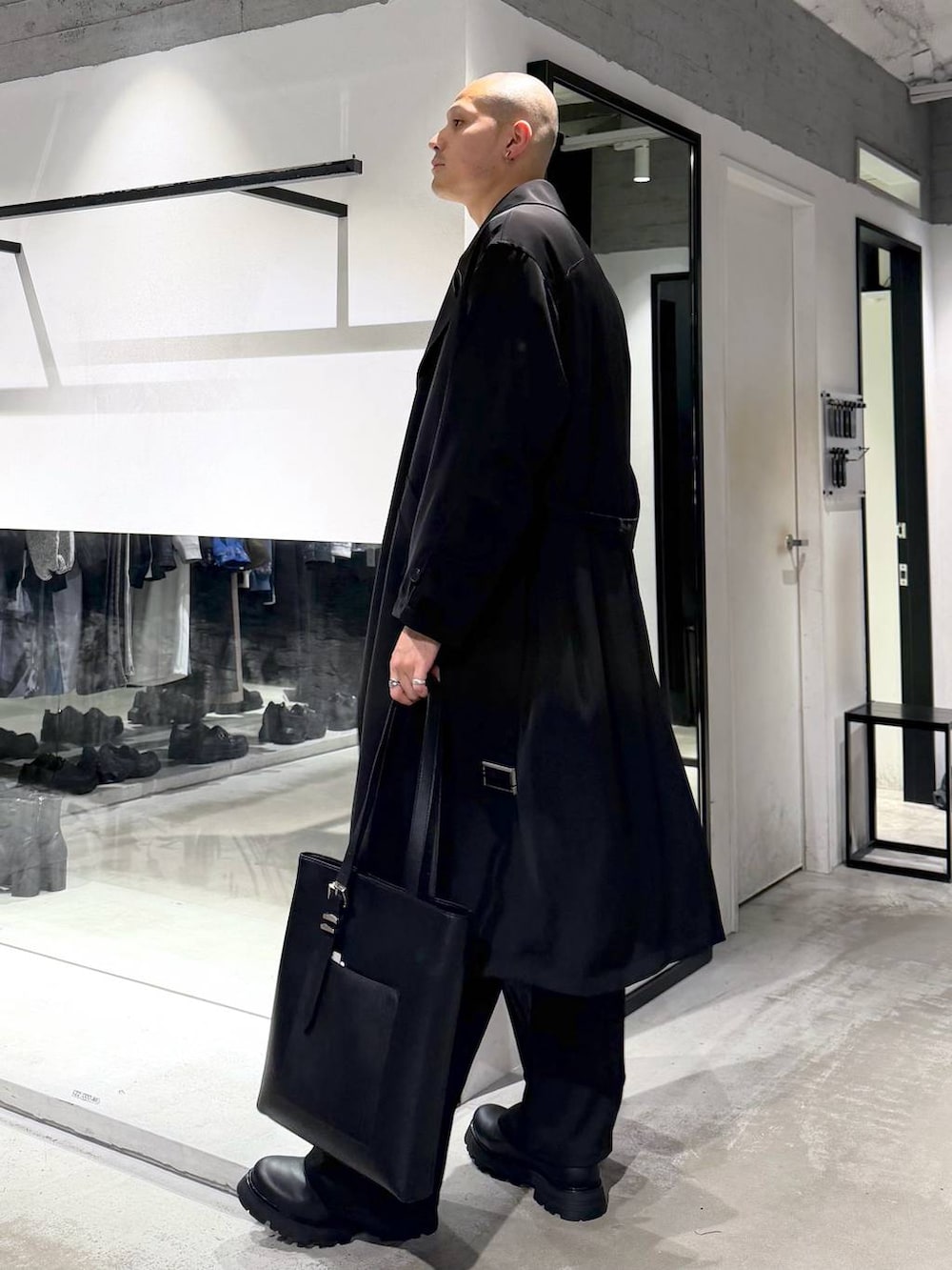 ブラック系のトートバッグ、ブラック系のドレスシューズ、ブラック系のトレンチコートを着用したメンズの春コーディネートの2枚目の写真