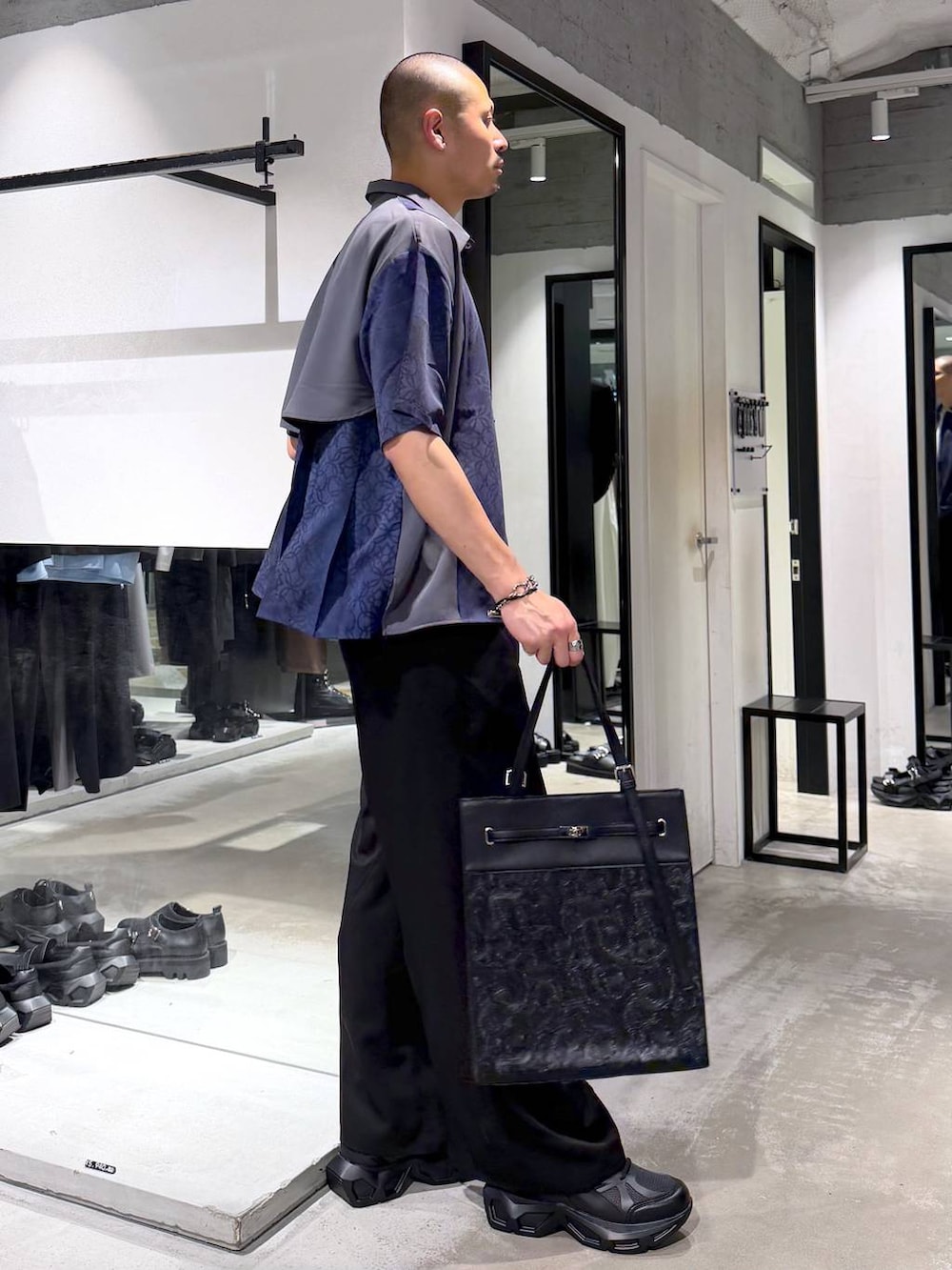 ブラック系のスニーカー、ホワイト系のTシャツ/カットソー、ブラック系のスラックスを着用したメンズの夏コーディネートの4枚目の写真