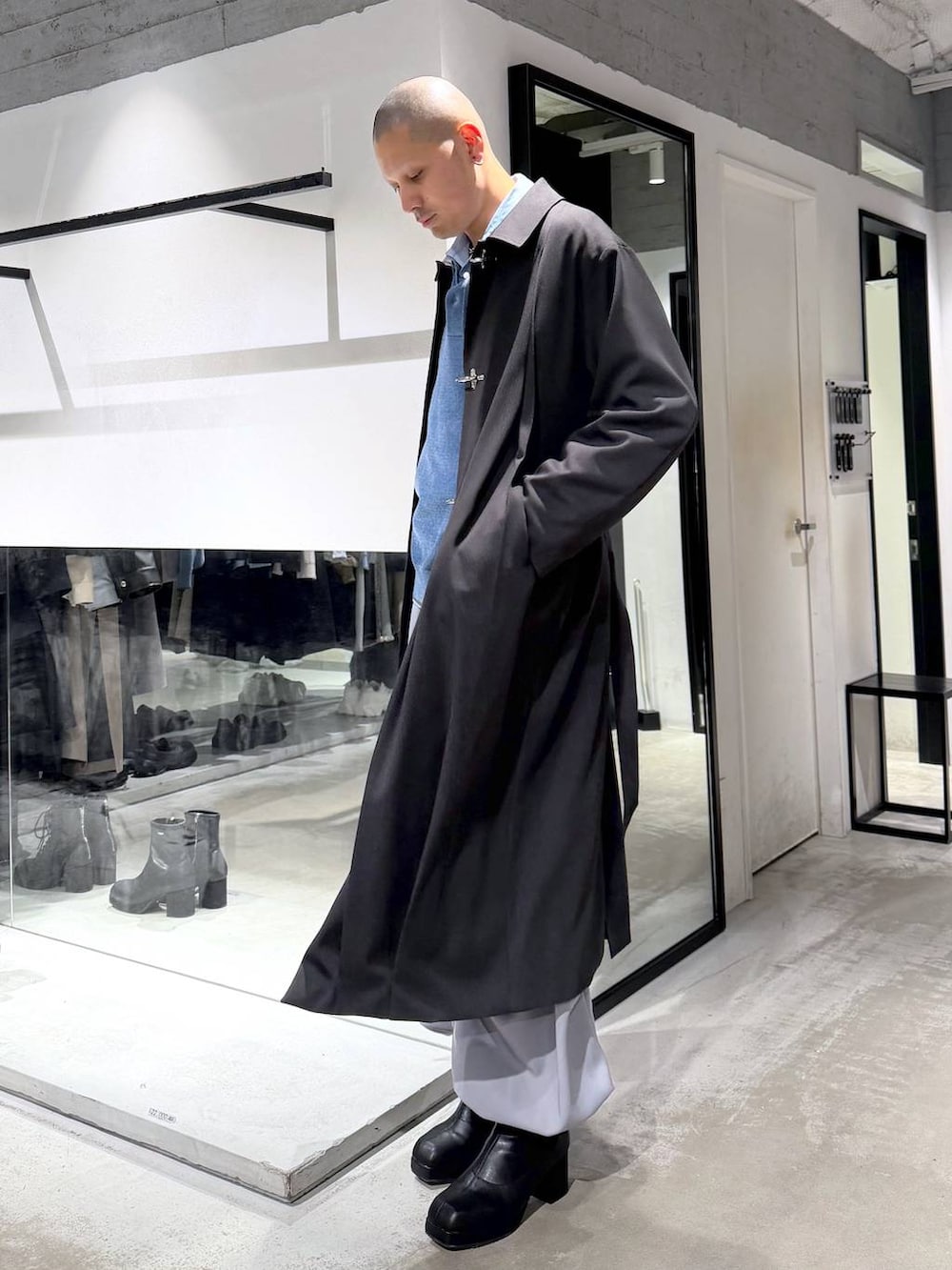 ブルー系のポロシャツ、ブラック系のブーツ、ブラック系のハンドバッグを着用したメンズの冬コーディネートの2枚目の写真