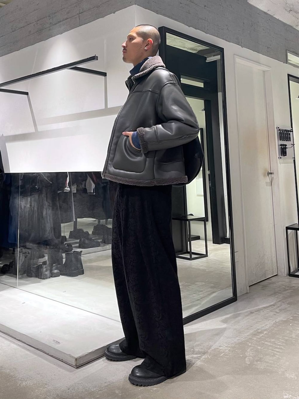 グレー系のブルゾン、ブラック系のブーツ、ブラック系のショルダーバッグを着用したメンズの冬コーディネートの2枚目の写真