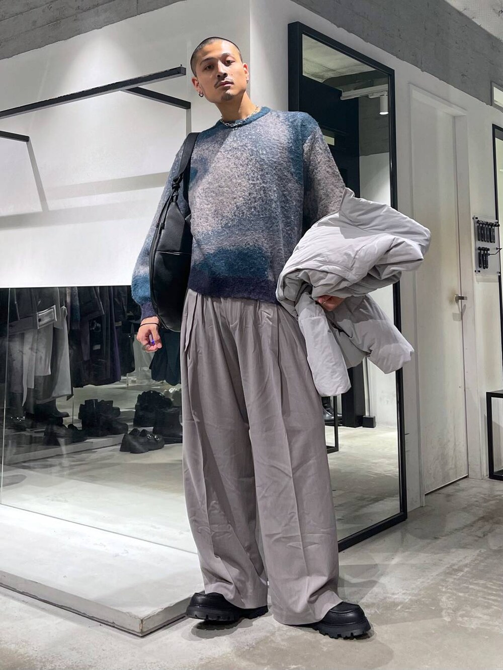 グレー系のダウンジャケット/コート、グリーン系のニット/セーター、ブラック系のショルダーバッグを着用したメンズの秋コーディネートの4枚目の写真