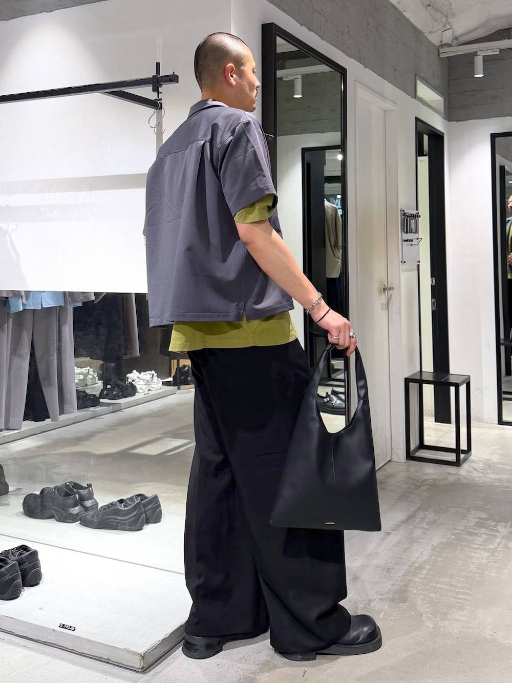 イエロー系のTシャツ/カットソー、ブラック系のトートバッグ、ブラック系のスラックスを着用したメンズの夏コーディネートの4枚目の写真