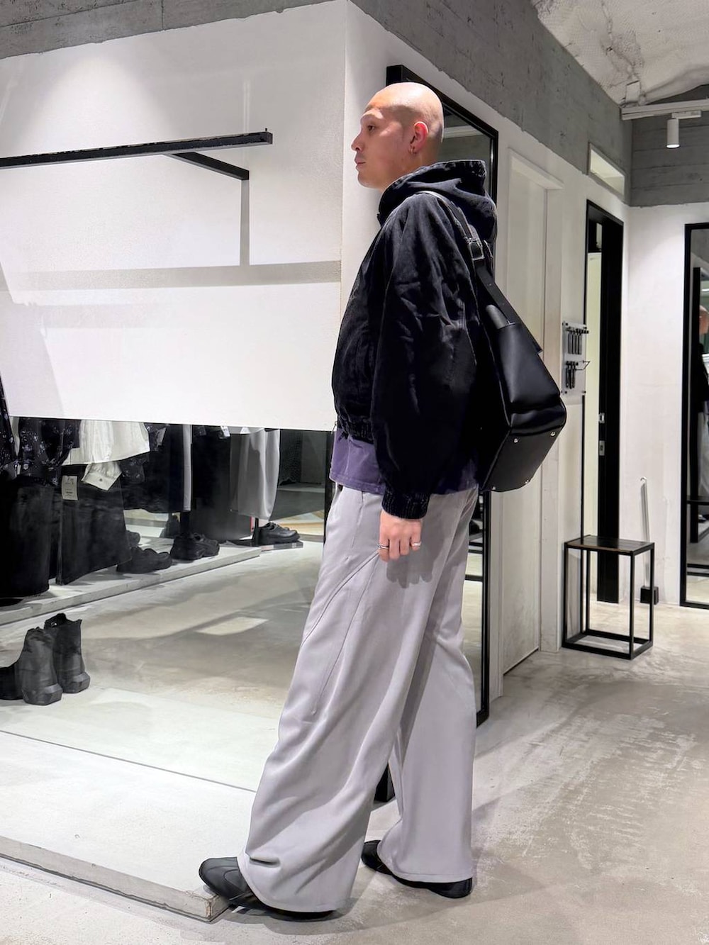 ブラック系のブルゾン、グレー系のスラックス、ブラック系のショルダーバッグを着用したメンズの春コーディネートの2枚目の写真